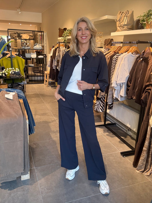 Donkerblauwe broek met knoopsluiting en wijde pijpen, zijzakken.