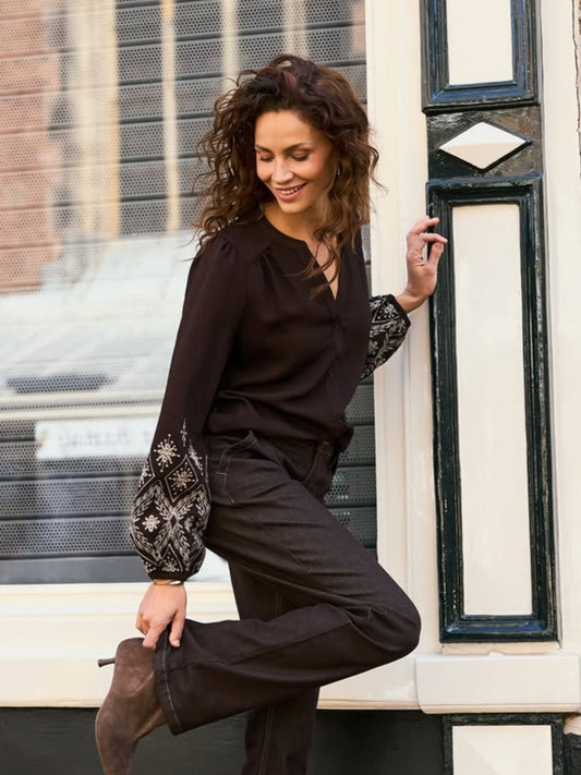 Donkere blouse met V-hals, knoopsluiting en geborduurde manchetten aan mouwuiteinden.