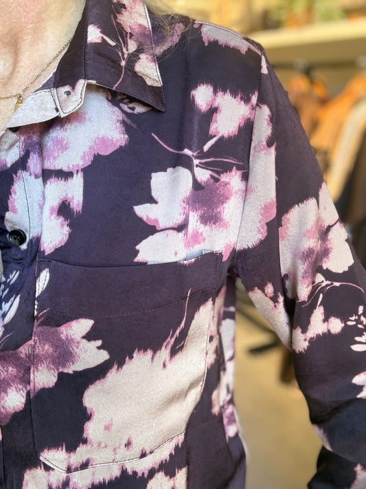 Knoopsluiting en bloemenprint op donkerpaarse blouse, close-up van stof