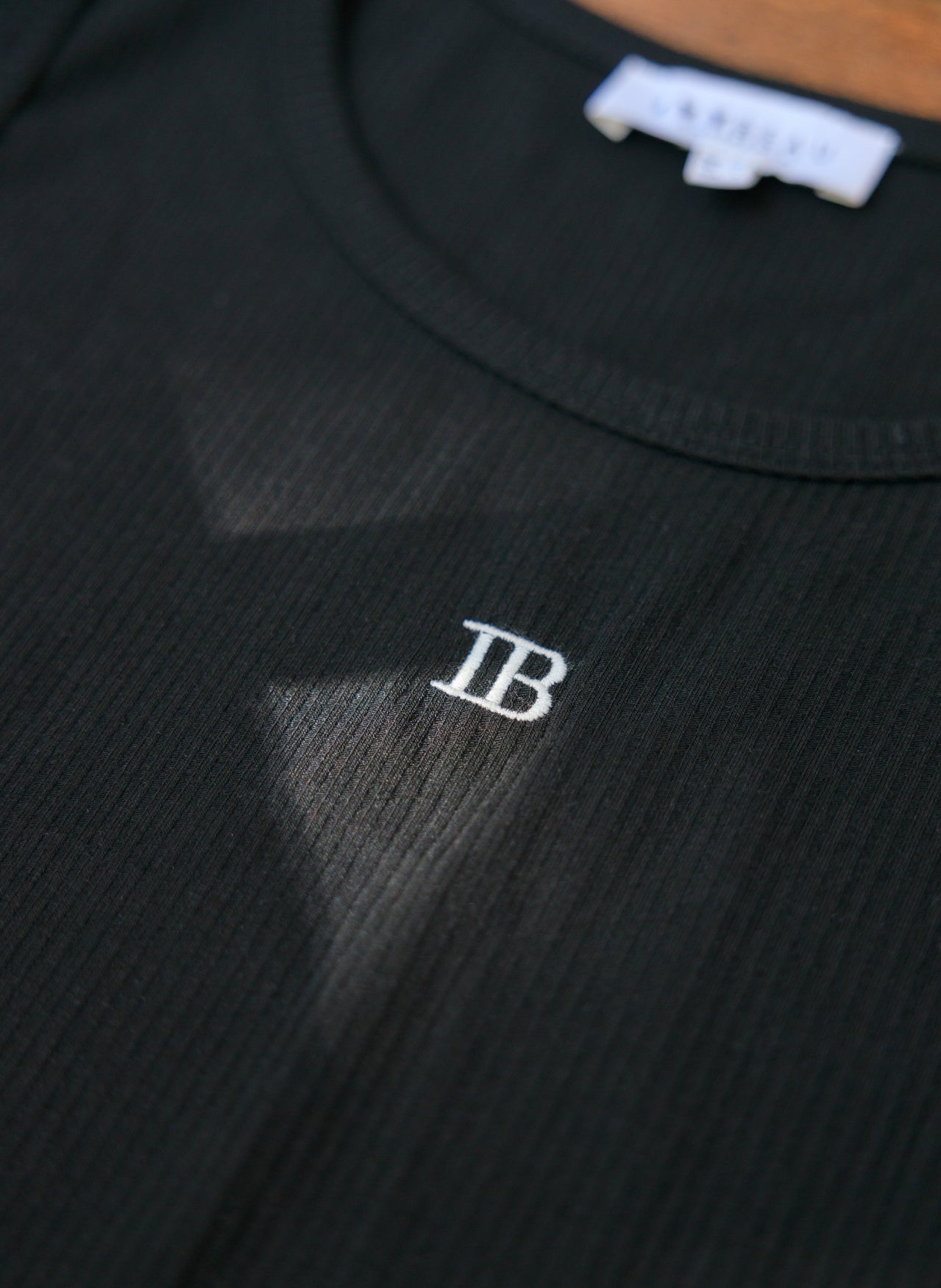 Zwarte mouwloze top met ribstructuur en wit IB-logo op de borst