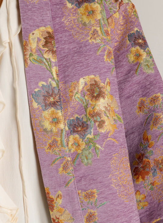 Detail van lila vestjasje met bloemenprint in oranje en groenige tinten