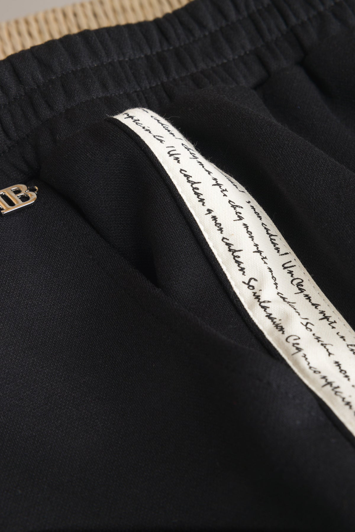 Zwarte broek tailleband met elastiek en wit label met logotekst