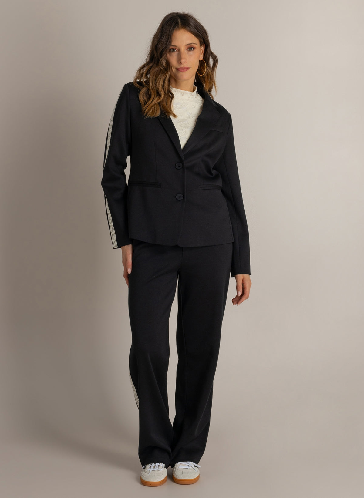 Zwarte blazer met revers en knoopsluiting, volledige look met bijpassende broek.