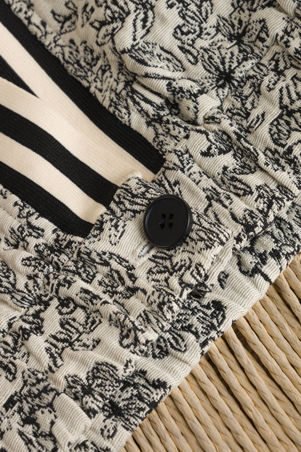 Detail van cropped jasje: zwart-wit print, contrastrand en zwarte ronde knoop