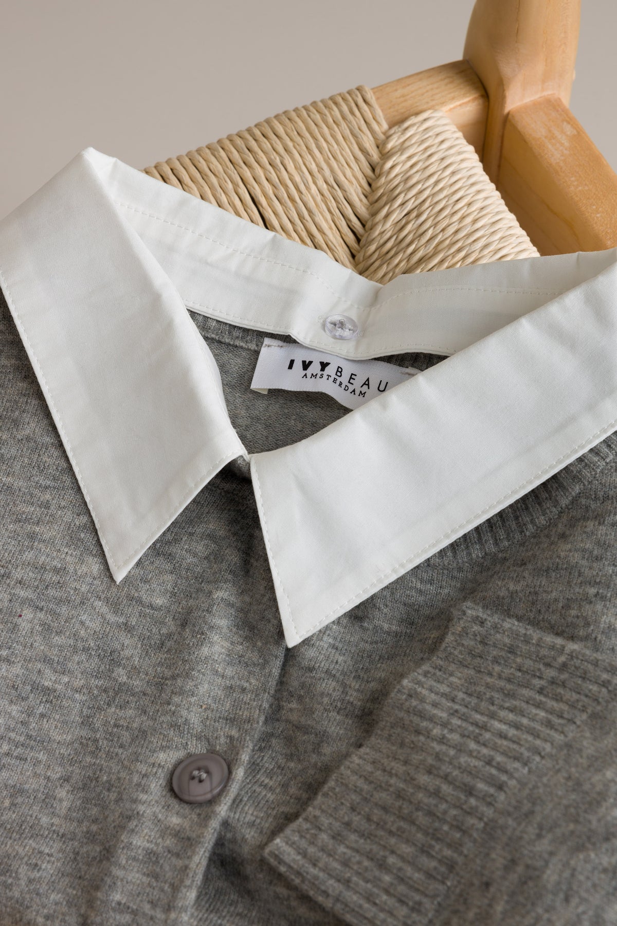Grijs melange vestdetail met witte kraag, knopen en merklabel