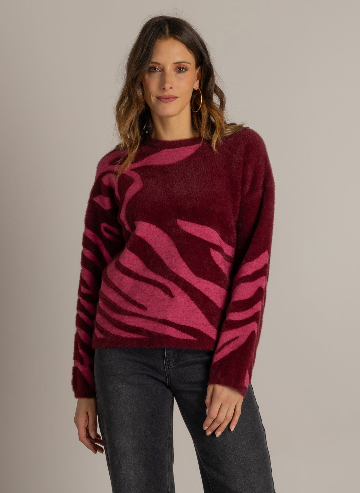 Trui met ronde hals, donkerwijnrode basis en roze abstract patroon op lange mouwen.