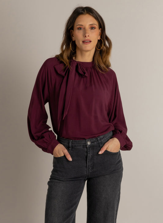 Donkerwijnrode blouse met strikdetail bij ronde hals en lange ballonmouwen