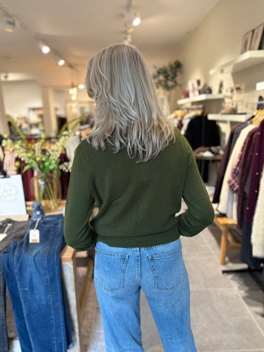 Mosgroen gemêleerd vest, van achteren gedragen met blauwe spijkerbroek
