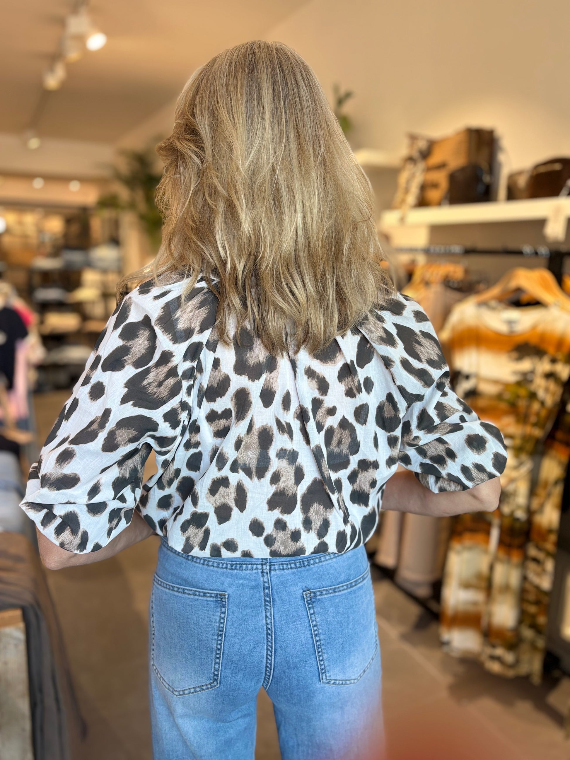 Luipaardprint blouse met halslijn en korte mouwen, witte basis met bruine vlekken.