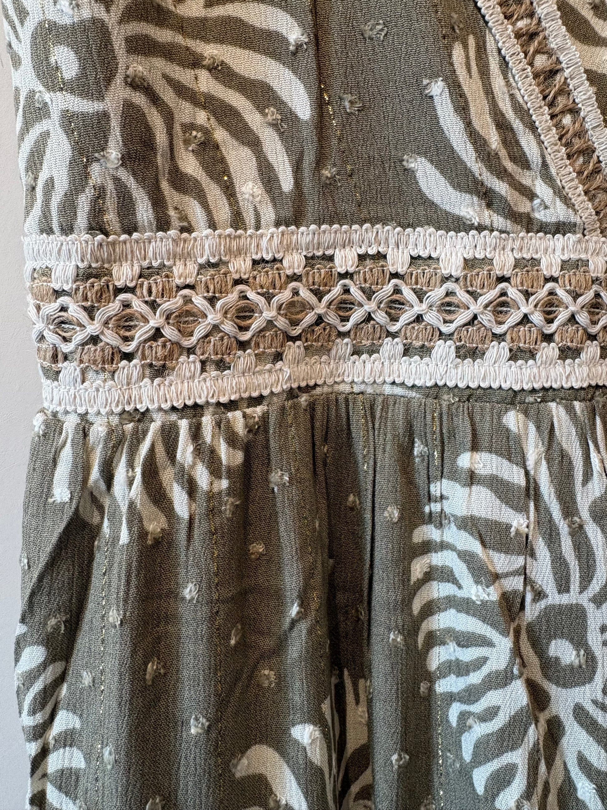 Khaki-grijze jurkdetail met witte print en geknoopte sierband rond de taille