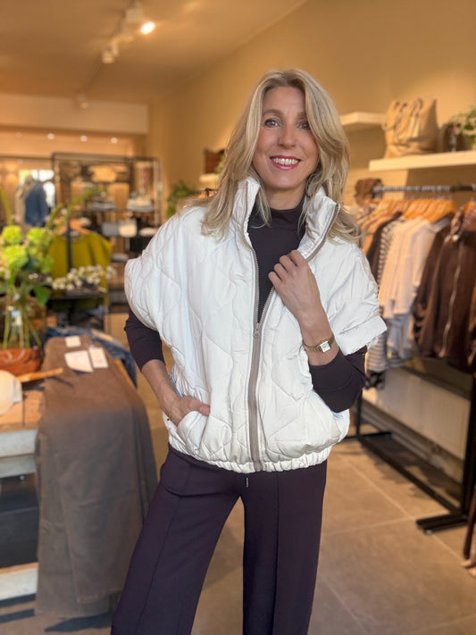 Gewatteerd gilet met rits, opstaande kraag, licht crème, vooraan gedragen.