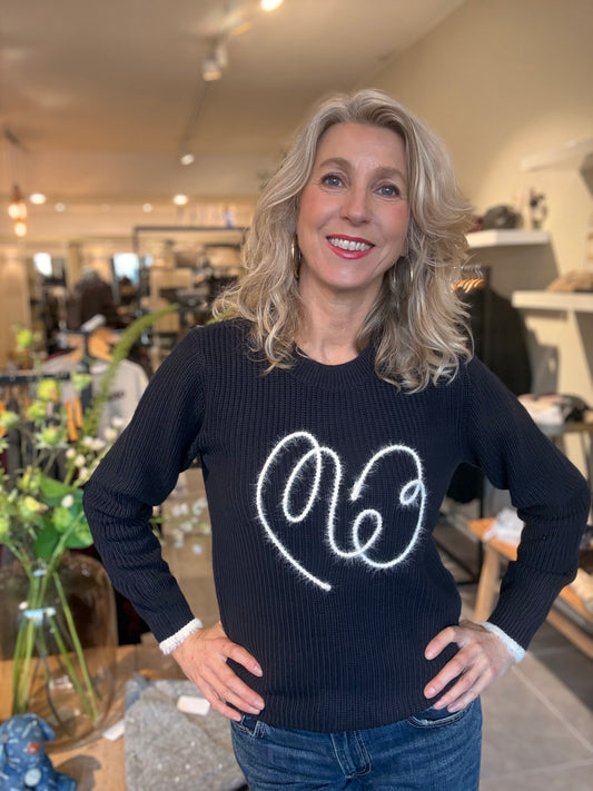 Donkerblauwe ribtrui met wit geborduurd logo en witte manchetten, gedragen van voren